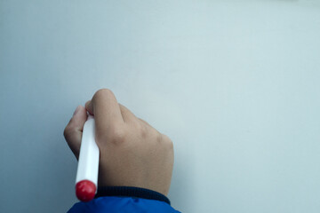 Child's hand with marker in hand, writing on a white Board, space for text