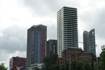 Modern tall residential buildings in Leuvehaven in Rotterdam. Houses in traditional architecture in the foreground. Mixture of architectural styles in the bank of a water channel.