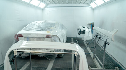 Automobile painting. Car painter with gun in chamber. Spray operation. 