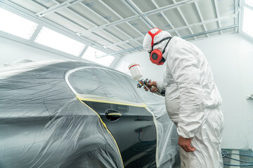 Automobile painting. Car painter with gun in chamber. Spray operation. 