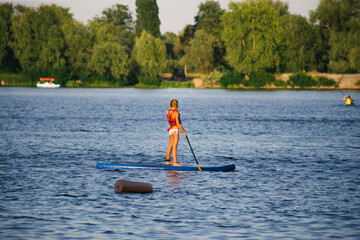 Young beautiful woman in a bikini on a SUP board in the river