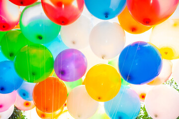 Sunlight against colorful gas-filled balloons attached to the yarn. Colorful balloons background.
