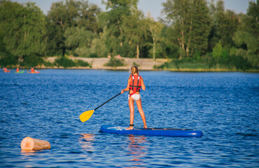 Young beautiful woman in a bikini on a SUP board in the river