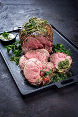 Traditional English barbecue lamb roast sliced with mint leaf and sauce offered as top view in a...