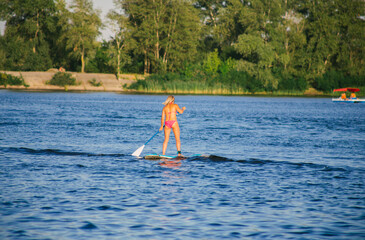 Young beautiful woman in a bikini on a SUP board in the river