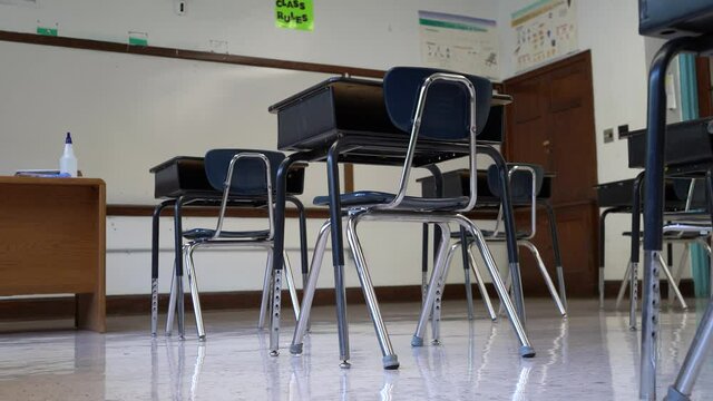 Floor view motion to the right showing empty school classroom with chairs under desks. Concept for pandemic.