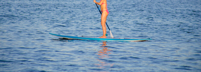 Young beautiful woman in a bikini on a SUP board in the river