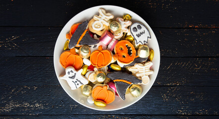 Halloween Jack o Lantern candy bowl with candy and halloween cookies Trick or Treat on black wooden background
