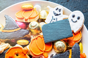 Halloween Jack o Lantern candy bowl with candy and halloween cookies Trick or Treat on black wooden background