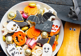 Halloween Jack o Lantern candy bowl with candy and halloween cookies, fresh pumpkin with eyes and witch hat. Trick or Treat on wooden background
