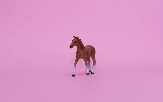 Plastic toy horse figure isolated on pink background