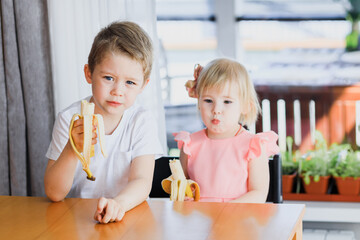 A girl and a boy eating a banana.