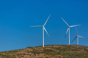View of a wind turbines on top of mountains, blue sky as background in Portugal