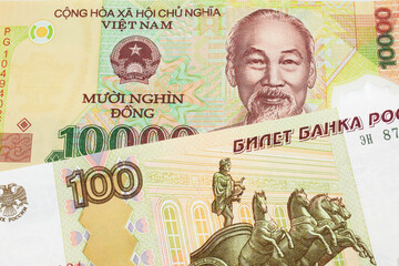 A macro image of a Russian one hundred ruble note paired up with a colorful, plastic ten thousand dong note from Vietnam.  Shot close up in macro.
