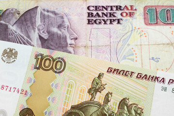 A macro image of a Russian one hundred ruble note paired up with a pink and purple ten pound bank note from Egypt.  Shot close up in macro.