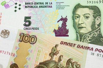 A macro image of a Russian one hundred ruble note paired up with a colorful five peso note from Argentina.  Shot close up in macro.