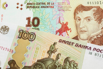 A macro image of a Russian one hundred ruble note paired up with a colorful ten peso note from Argentina.  Shot close up in macro.