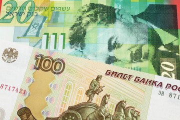 A macro image of a Russian one hundred ruble note paired up with a green and white twenty shekel bill from Israel.  Shot close up in macro.