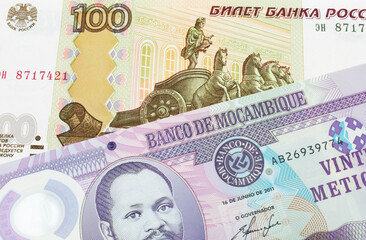 A macro image of a Russian one hundred ruble note paired up with a purple, plastic twenty metical note from Mozambique.  Shot close up in macro.