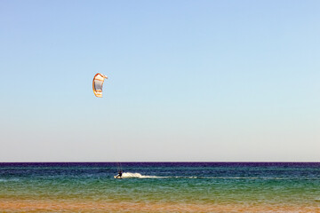a kitesurfer surfing on the smooth azure water. recreational sport. A Man Rides A Kiteboarding In The Sea Water. extreme sport. Jump