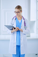 Smiling female doctor with a folder in uniform standing