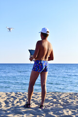 A man controls a quadrocopter on the seashore. Filming from above. Universal video equipment.