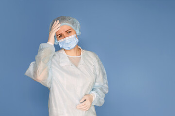 Portrait of a young woman doctor surgeon on a blue background, copy space