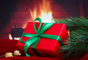 Close up wrapping and Decorating Christmas Present or gift with gold balls and christmas tree branch on red sweater with fireplace on background.Xmas mood and atmosphere. Winter holiday concept