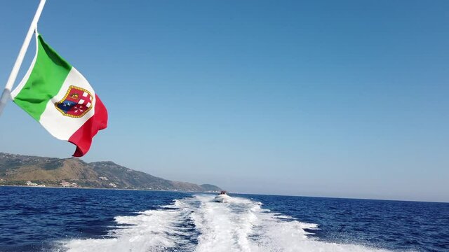 La bandiera italiana della barca che sventola sulla scia del mare.