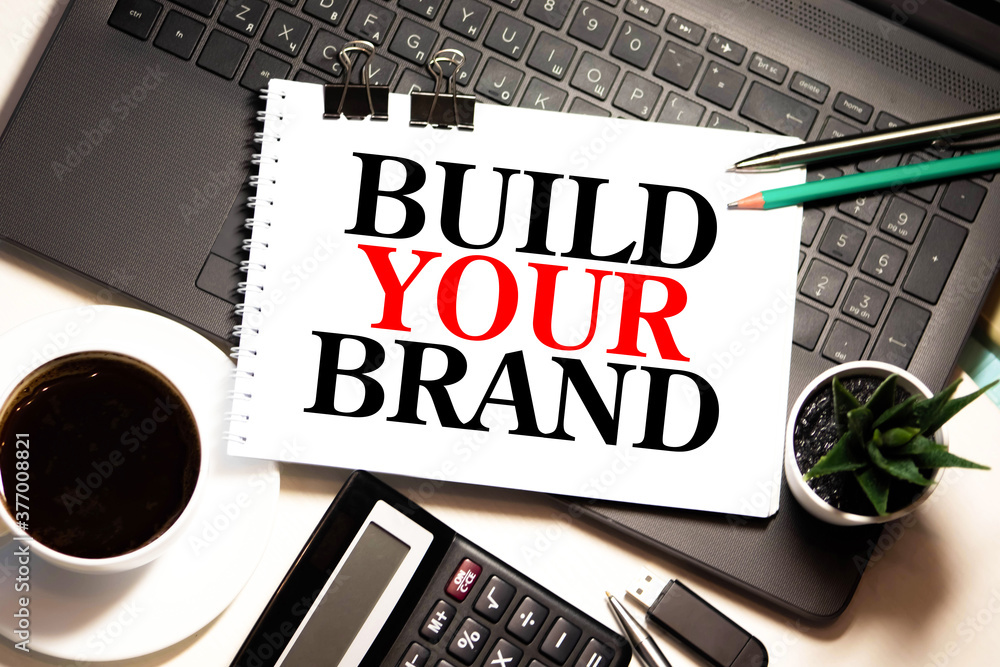 Poster build your brand typed on yellow paper on top of computer keyboard.
