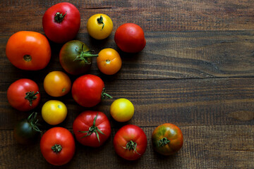 Harvest concept. Different types of tomatoes on wooden background with copy space. Top view, flat...