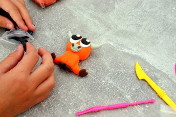 The girl is holding a figurine in the form of a bull made of airy plasticine, children's creativity, with her own hands, a symbol of the year 2021.