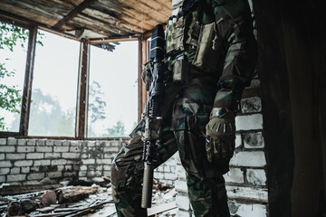 Weapons close-up on a military man standing inside the building and waiting for command.
