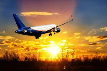 A silver jet is is taking off on background of bright red sunset.