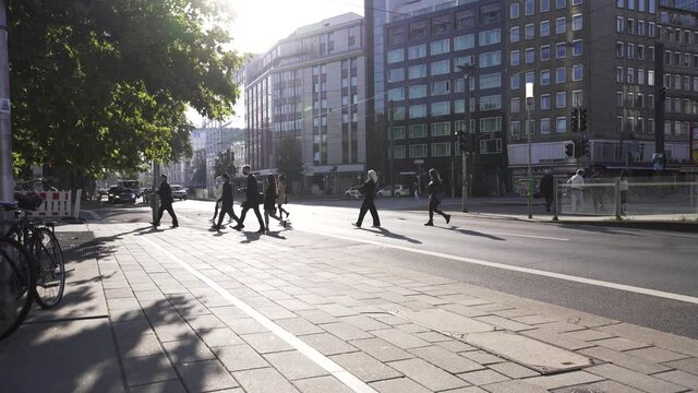 D&uuml;sseldorf, Germany - many pedestrians crossing a busy/ urban street in the city center while sunrise.