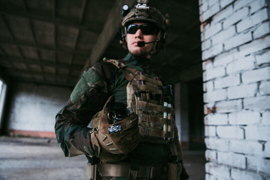 Military man ready to pull a check and to throw a smoke grenade at the building during combat.