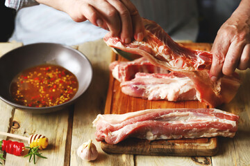 The chef marinates raw ribs. Barbecue pork ribs cooking.