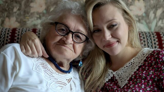 Senior grandmother and adult granddaughter smiling

