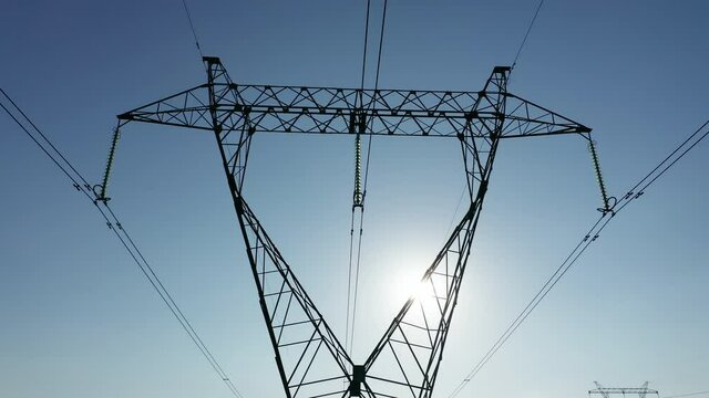 Transmission tower supporting an overhead high voltage power line - close up. The pylon carries wires that transport electric power from generating stations to electrical substations. Aerial footage.