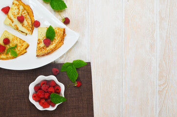 Pancakes with raspberries pancakes on a white ceramic plate in the shape of a heart top view with copy space for text. The concept of the Maslenitsa week holiday