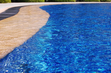 Fototapeta na wymiar 青いスイムングプールの美しい曲線のプールサイド