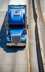 Classic blue big rig semi truck transporting cargo in refrigerated semi trailer with refrigerator...