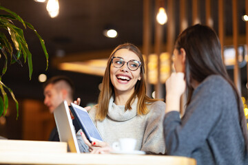 Two girls having a meeting at a modern cafe. Happy smiling expressions,