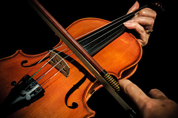 Violin with hands playing on black background