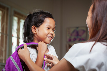 Asian child girl is smiling. Mother is helping her child girl get ready for school.