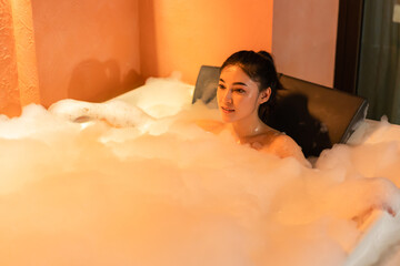 woman taking a bubble bath in bathtub at the night