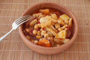Mondongo a la espanola or cayos a la espanola. Presented in an earthenware bowl, on a wooden table View at 45 degrees.