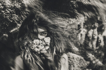 beautiful young woman cover her face with flowers. black and white portrait. conceptual tilt shift effect.