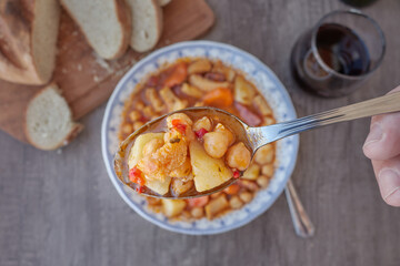 Mondongo a la espanola or cayos a la espanola. Presented on a white vintage plate with blue details on a wooden table Top view. View at 45 degrees. Foreground,