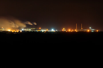 Night view of industrial district of the city and smoke pipes of factory